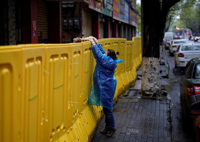 •       Người dân chuyển thực phẩm qua rào chắn khu cách ly. (Ảnh: Reuters)