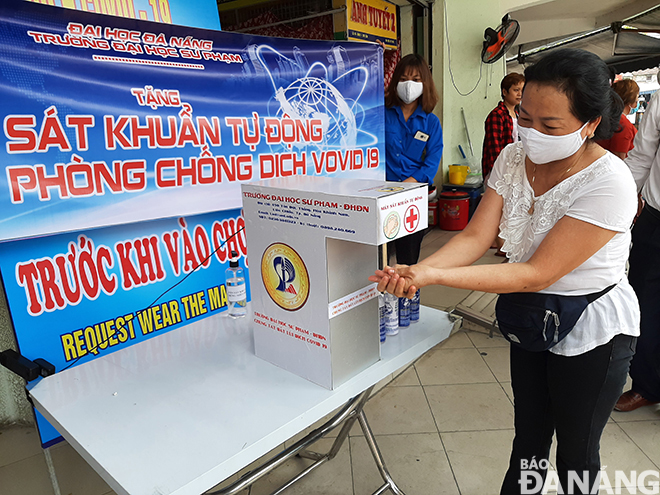 A shopper using an automatic hand sanitiser dispenser at a local market