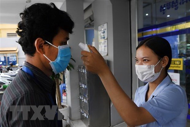 A client's body temperature is taken in front of a bank in Phnom Penh, Cambodia (Photo: AFP)