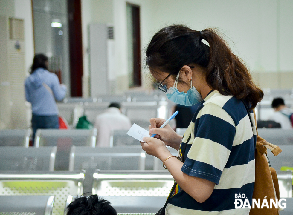 A female passenger is filling in a health form at the station