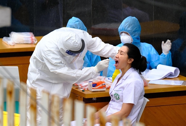 A health worker is seen collecting a nasopharyngeal swab from a doctor at Bach Mai Hospital in Ha Noi on April 2 to test for SARS-CoV-2 infection, after many employees working for a food catering company to the hospital tested positive.