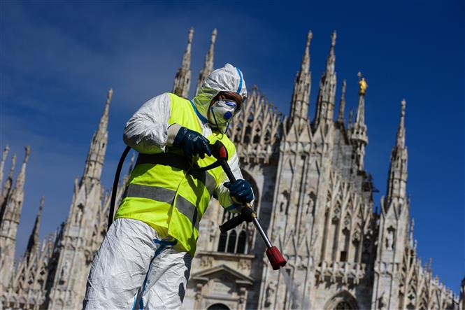 Nhân viên phun thuốc khử trùng nhằm ngăn chặn sự lây lan của dịch Covid-19 tại Milan, Italy, ngày 31-3-2020. Ảnh: AFP/TTXVN