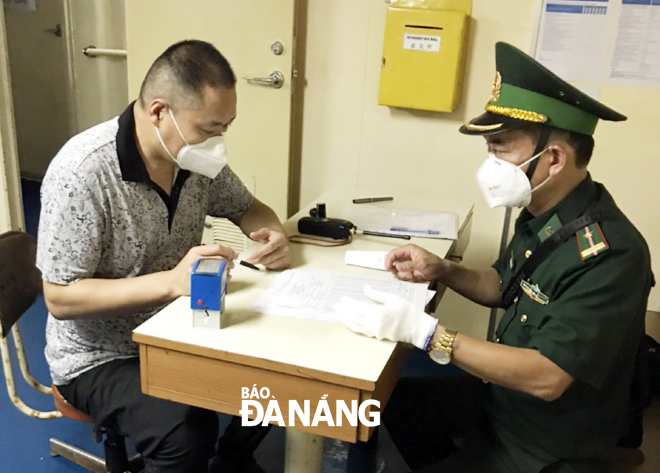 Cán bộ Biên phòng tiến hành làm công tác nhập cảnh cho người dân tại vịnh Đà Nẵng sau khi họ đã được kiểm tra y tế, bảo đảm về sức khỏe. 			         Ảnh: HƯƠNG SEN