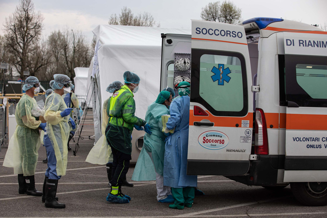 Các nhân viên y tế đưa bệnh nhân Covid-19 đến một bệnh viện dã chiến ở thành phố Cremona của Ý. 			                              Ảnh: Getty Images