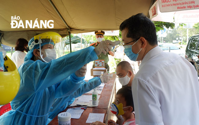 A healthcare worker checking the temperature of Deputy Secretary Nguyen Van Quang at a local checkpoint