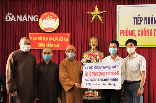 Vice Chairman of the municipal Fatherland Front Committee Le Van Minh (2nd right) receiving donations from the Executive Board of the city's Buddhist Sangha 