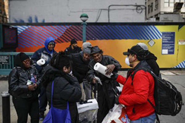 Felix Guzman và vợ Virna trao tặng găng tay và khăn lau vệ sinh cho một nhóm người vô gia cư.