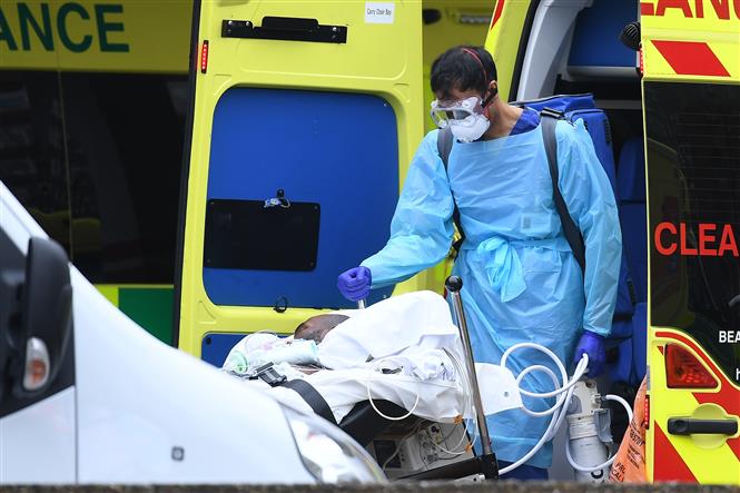 Nhân viên y tế chuyển bệnh nhân mắc COVID-19 từ xe cứu thương vào bệnh viện St Thomas ở London, Anh ngày 31/3/2020. Ảnh: AFP/TTXVN