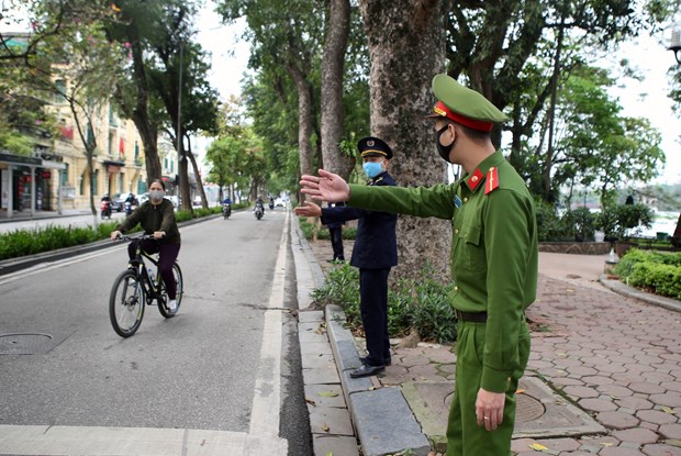 Officers remind a cyclist near Hoan Kiem Lake in Ha Noi about social distancing (Photo: VNA)