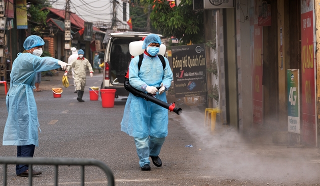 Medical workers spray steriliser in Ha Loi Village where two Covid-19 patients live