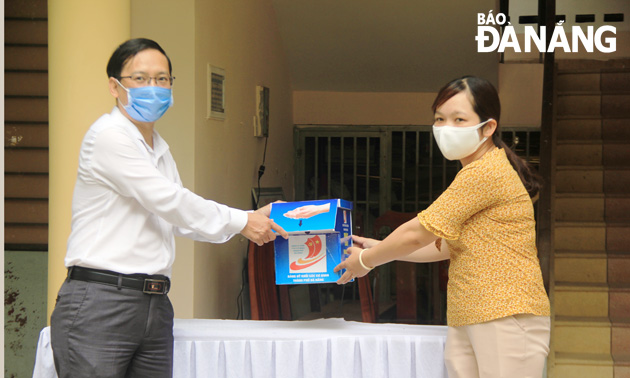 Mr Ha Duc Hoai, Deputy Secretary of the municipal Party Committee of the Government Department and Agency Block, (left) donating an automatic hand sanitiser dispenser to leader of the Hoa Phong Commune
