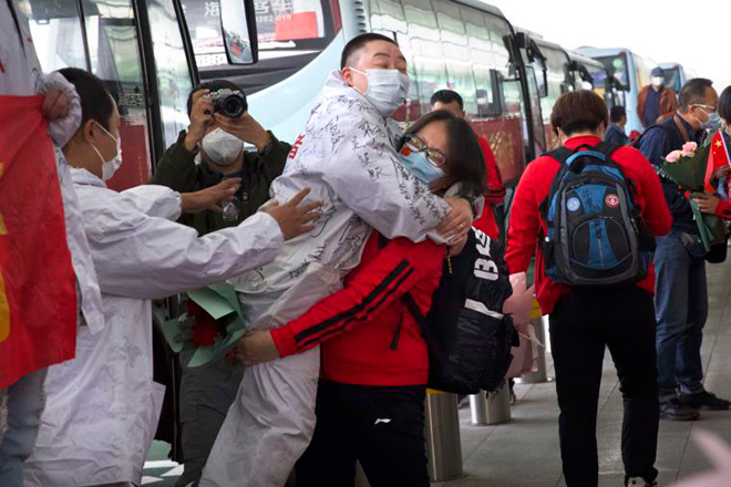 Tại sân bay quốc tế Thiên Hà ngày 8-4, một nhân viên y tế (áo đỏ) ôm đồng nghiệp ở Vũ Hán khi cô sắp trở về tỉnh Cát Lâm. Nhân viên y tế này đã đến Vũ Hán để tham gia công tác chống dịch và bị kẹt lại nơi đây.  						Ảnh: AP