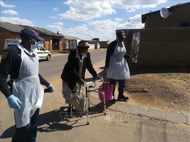 Cảnh sát giúp đỡ một người già trên đường đi mua thực phẩm tại ngoại ô thủ đô Pretoria hôm 7/3. Ảnh: Phi Hùng (P/v TTXVN tại Nam Phi)