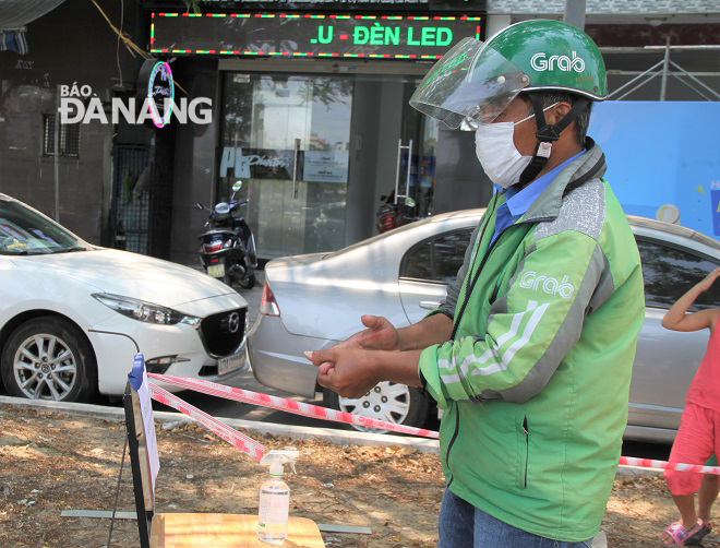 A Grab Bike driver cleaning his hands before receiving a free portion of rice