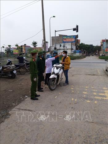 Kiểm soát thân nhiệt người dân tại chốt chặn ra vào thôn Hạ Lôi. Ảnh: Nguyễn Cúc/TTXVN