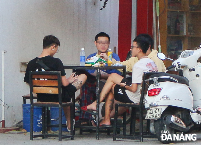 Một nhóm thanh, thiếu niên tụ tập tại bàn uống nước của một cửa hàng tiện lợi trên đường Hồ Nghinh, quận Sơn Trà. Không một ai đeo khẩu trang. Ảnh: XUÂN SƠN