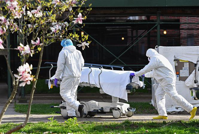 Nhân viên y tế chuyển thi thể bệnh nhân mắc Covid-19 từ nhà xác dã chiến tới Trung tâm Y tế Do Thái Kingsbrook ở New York, Mỹ. Ảnh: AFP/TTXVN