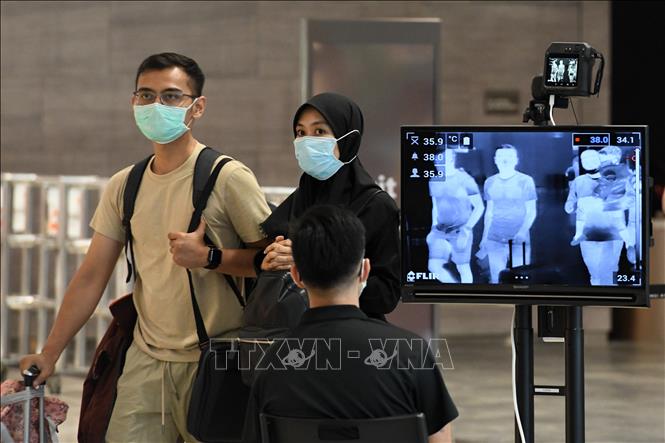 Đo thân nhiệt phòng nhiễm COVID-19 tại sân bay ở Singapore ngày 27/2. Ảnh: THX/TTXVN