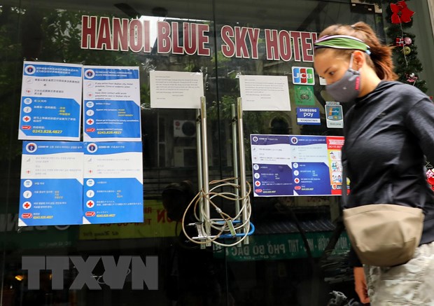 Một khách nước ngoài bước qua một khách sạn ở Hà Nội đóng cửa vì COVID-19. (Ảnh: Lâm Khánh/TTXVN)