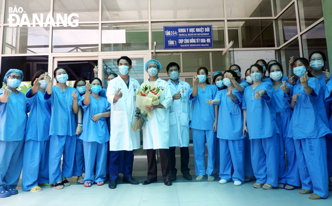 Bác sĩ Lê Đức Nhân, Giám đốc Bệnh viện Đà Nẵng (thứ 5, từ trái sang) tặng hoa tập thể khoa Y học nhiệt đới sau khi ca bệnh cuối cùng nhiễm SARS-CoV-2 được điều trị thành công. Ảnh: PHAN CHUNG