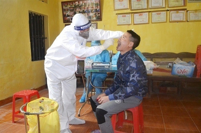 A medical worker takes a sample of a resident in Ha Loi Village for testing for Covid-19.