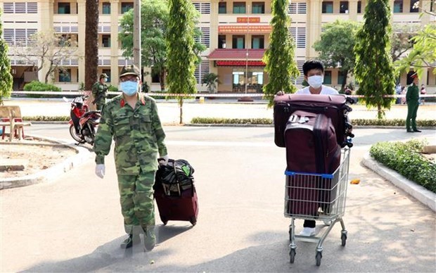 Soldier helps transport luggage of a man who finishes concentrated quarantine (Source: VNA)