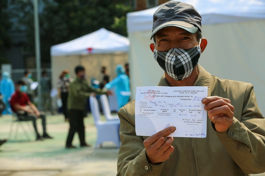Ông Nguyễn Hữu Tèo, một người dân tại Tây Tựu vui mừng khi cầm trên tay tờ kết quả âm tính. (Ảnh: Tùng Lâm/Vietnam+)