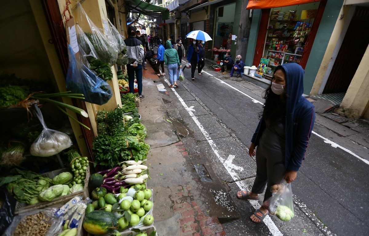Tại những khu chợ dân sinh ở Hà Nội, đường phố được kẻ vạch sơn, quy định khoảng cách giữa người mua và người bán. (Ảnh: Minh Quyết - TTXVN)