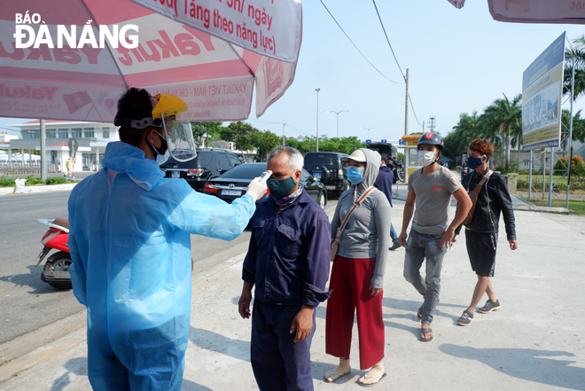 A medical worker checking the temperatures of arrivals to the city at a local checkpoint 