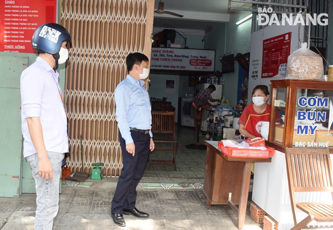 Representatives from the Nam Duong Ward authorities reminding an owner of an eatery to strictly follow the city’s infection prevention and control measures