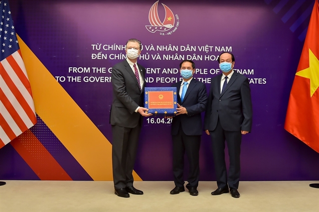 US Ambassador to Việt Nam Daniel J Kritenbrink (left) receives the symbolic token representing gifts of face masks from Vietnamese Government and people, from Vietnamese deputy foreign minister Bùi Thanh Sơn and Chairman of Government Office Mai Tiến Dũng. 