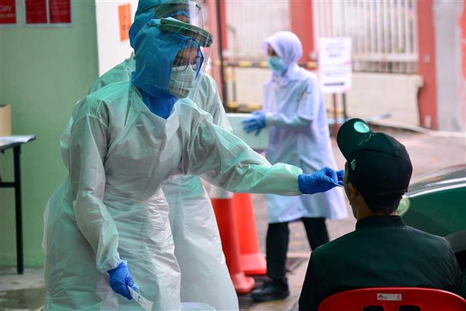 Nhân viên y tế lấy mẫu dịch xét nghiệm COVID-19 cho người dân tại bệnh viện ở Damansara, Malaysia. Ảnh: THX/ TTXVN