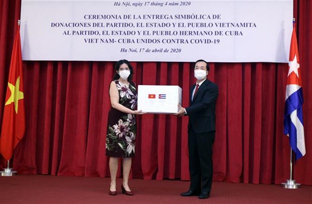 Minister of Construction Pham Hong Ha (R) presents the token of the relief package to Cuban Ambassador Lianys Torres Rivera (Photo: VNA)