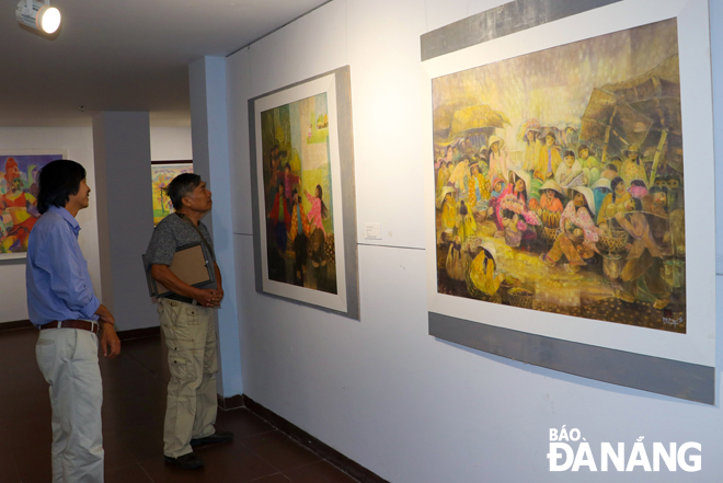 Họa sĩ Hồ Đình Nam Kha (phải) và tác phẩm của anh trưng bày tại Triển lãm tranh lụa Đà Nẵng năm 2019. Ảnh: NGỌC HÀ	