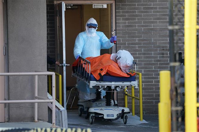 Nhân viên y tế chuyển thi thể bệnh nhân mắc Covid-19 ra nhà xác dã chiến bên ngoài một bệnh viện ở New York, Mỹ ngày 4-4-2020. Ảnh: AFP/TTXVN