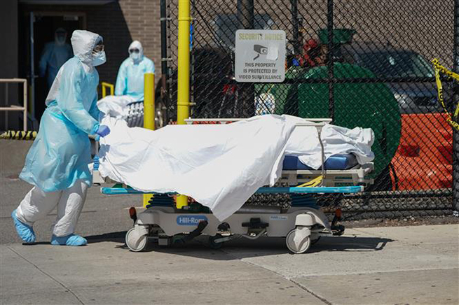  Nhân viên y tế chuyển thi thể bệnh nhân mắc Covid-19 ra nhà xác dã chiến bên ngoài một bệnh viện ở New York, Mỹ ngày 6-4-2020. Ảnh: AFP/TTXVN
