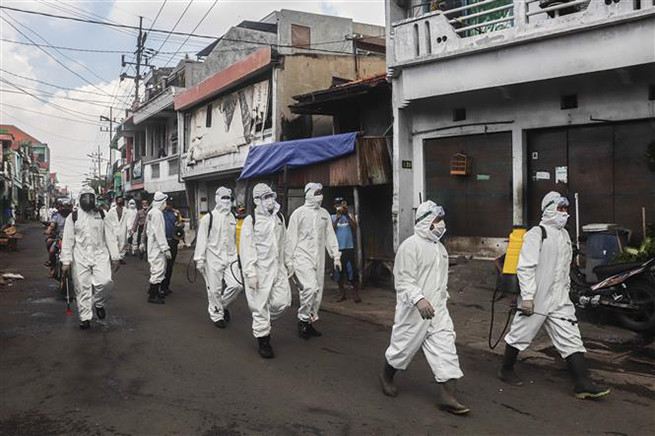  Binh sĩ và cảnh sát Indonesia phun thuốc khử trùng nhằm ngăn chặn sự lây lan của dịch Covid-19 tại Surabaya ngày 16-4-2020. Ảnh: THX/TTXVN