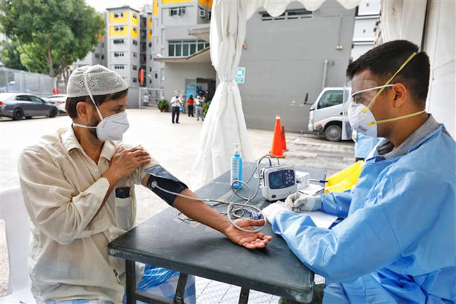  Lao động nước ngoài được kiểm tra y tế tại Singapore ngày 8-4-2020. Ảnh: THX/TTXVN