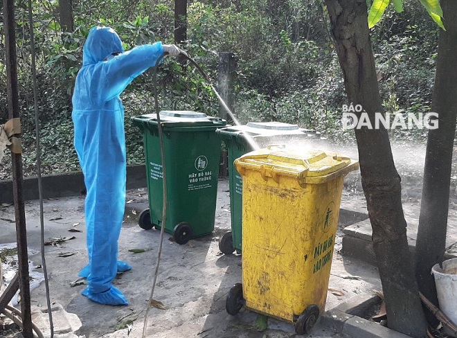 A worker cleaning and disinfecting waste bins with Chloramine B