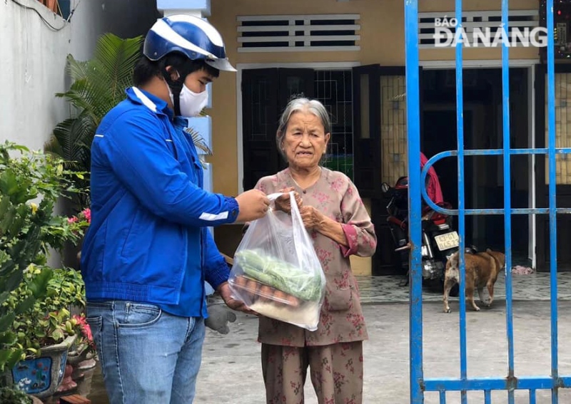 A Youth Union member delivering a food package to a poor family in Cam Le District