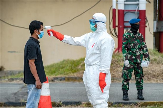 Nhân viên y tế kiểm tra thân nhiệt người dân nhằm ngăn chặn sự lây lan của dịch Covid-19 tại Bắc Sumatra, Indonesia. (Ảnh: THX-TTXVN)