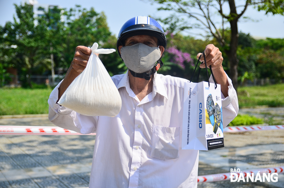A man expressing his joy with bags of free rice and face masks