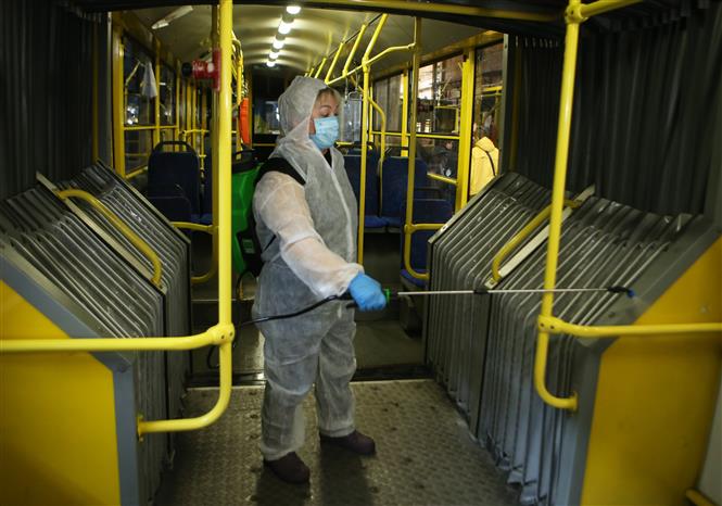 Nhân viên phun khử trùng một xe buýt nhằm ngăn chặn sự lây lan của dịch COVID-19 tại Kiev, Ukraine ngày 12/3/2020. Ảnh: THX/TTXVN