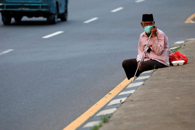  Một người lao động Indonesia ngồi bên lề đường khi đang tìm cách trở về quê. Ảnh: Straits Times