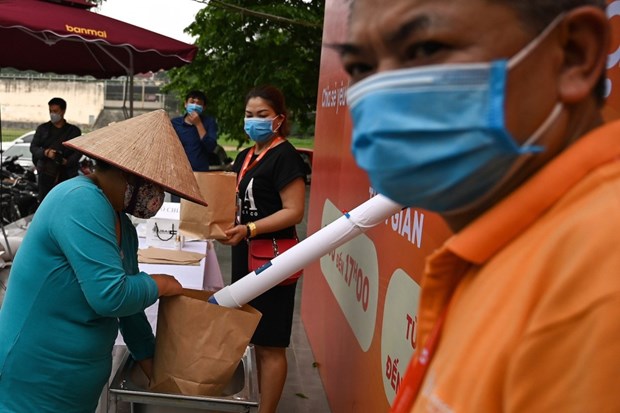 A resident wearing a face mask fills a paper bag with free rice amid Vietnam’s nationwide social distancing as a preventive measure against the spread of Covid-19 (Photo: AFP)