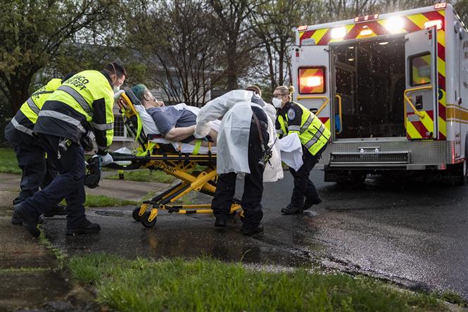  Nhân viên y tế chuyển bệnh nhân mắc COVID-19 lên xe cứu thương tại Glen Burnie, bang Maryland, Mỹ ngày 13/4/2020. Ảnh: AFP/TTXVN