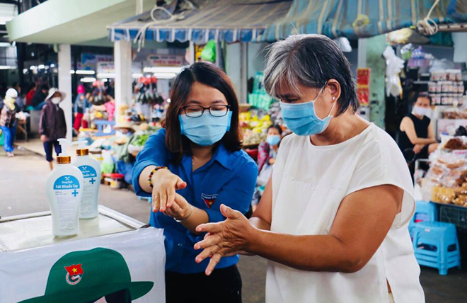 Đoàn viên Sở Y tế hướng dẫn người dân sử dụng máy rửa tay sát khuẩn nhanh tại chợ.                       	