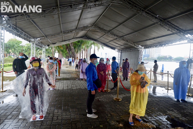 Despite the wet weather on Friday morning, a large number of people lining up two meter apart on Tran Hung Dao Street to use the rice dispenser 