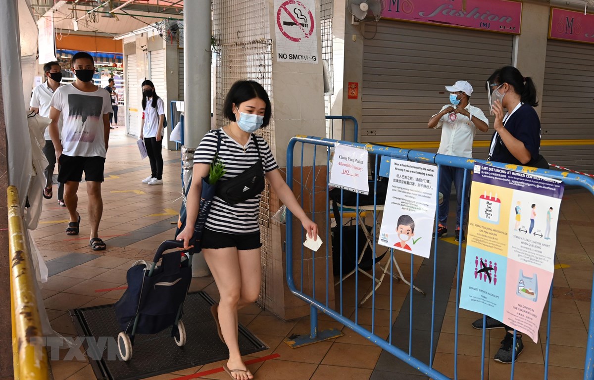 Người dân đeo khẩu trang và thực hiện giãn cách xã hội phòng lây nhiễm dịch Covid-19 tại một chợ ở Singapore, ngày 22-4-2020. (Ảnh: AFP/TTXVN)