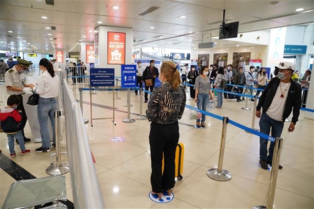 Flight passengers at Noi Bai International Airport in Ha Noi keep the distance. Although the national social distancing requirement has been eased, physical distancing is still required in the country.